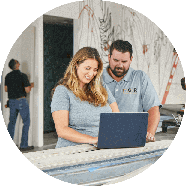 Construction business owners review notes on their laptop while on a job site.